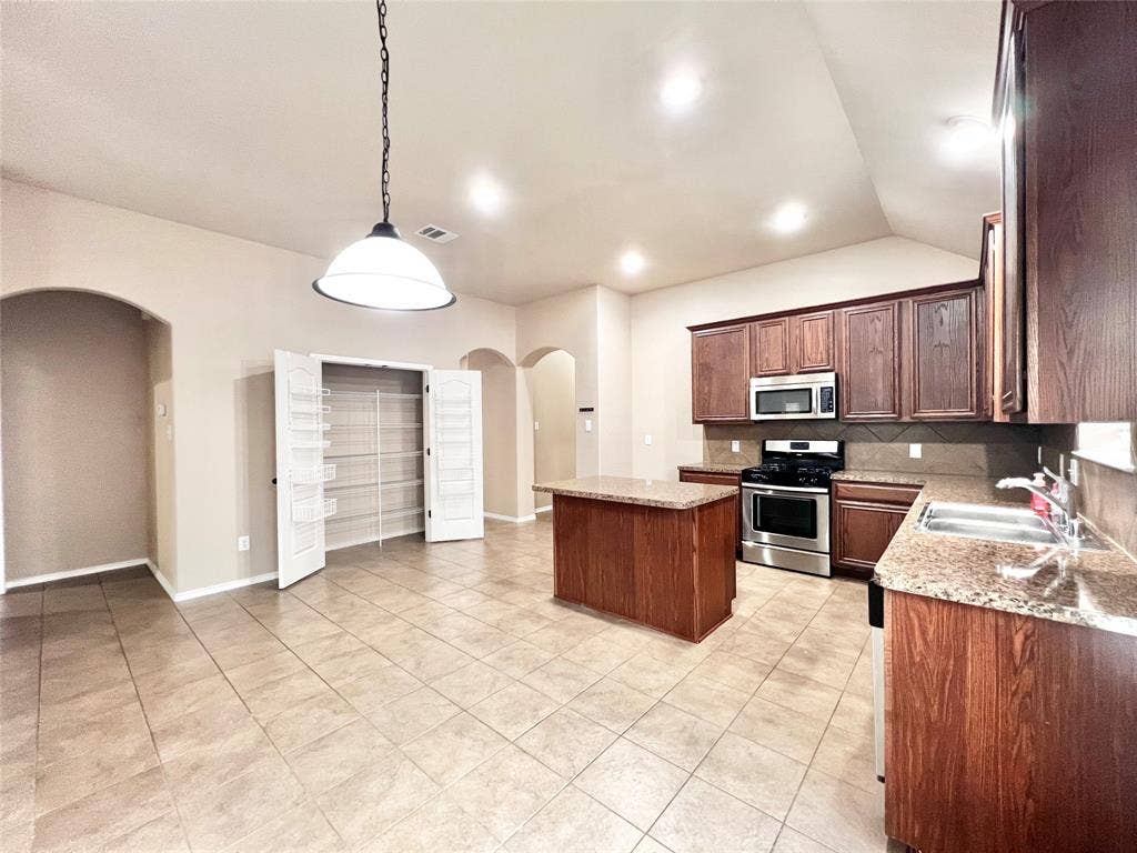 5204 Bear Valley Drive, McKinney, TX 75071 Spacious kitchen featuring a central island, wood cabinetry, stainless steel appliances, and tile flooring