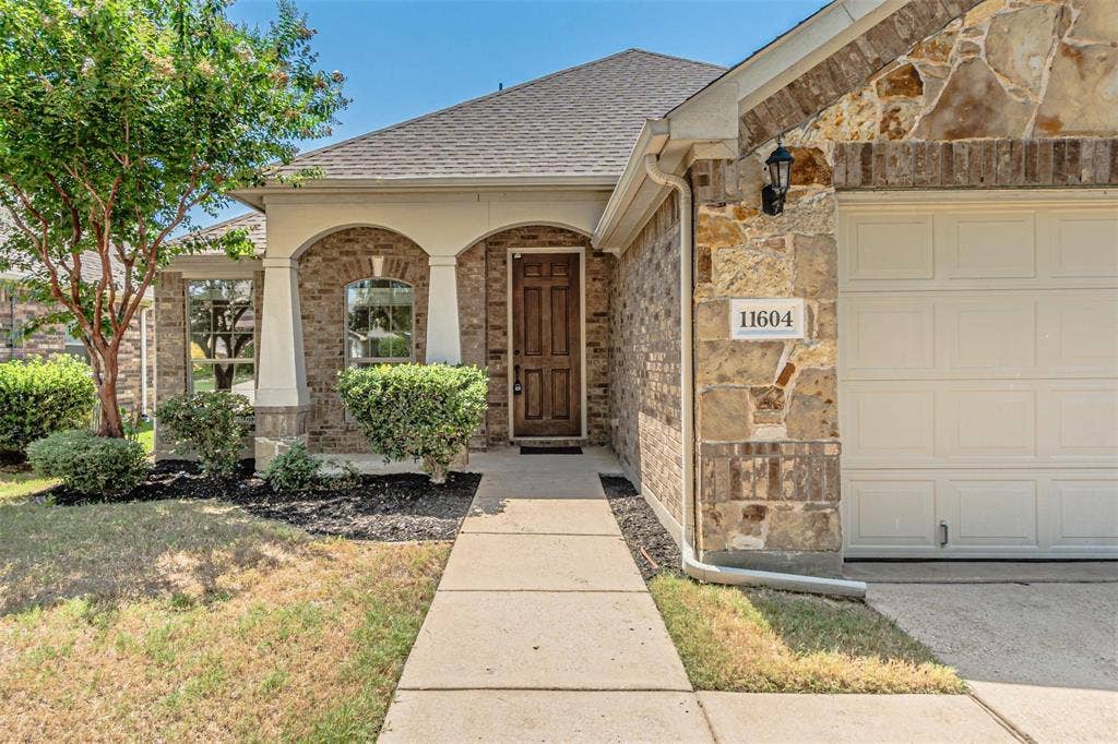 Brick and stone exterior featuring an arched entryway, wood-paneled front door, and an attached garage