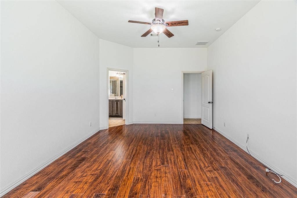 Wood-finish flooring, vaulted ceilings, and a ceiling fan with integrated lighting
