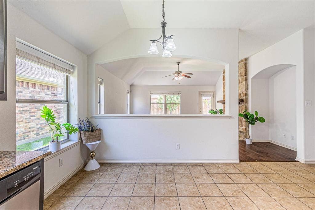 Vaulted ceiling with a chandelier, tile flooring, and a window with blinds