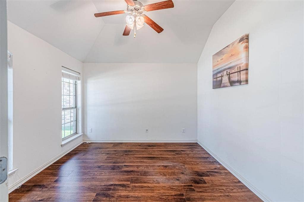 Vaulted ceiling, wood-finish flooring, ceiling fan, and a single window