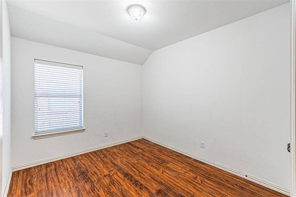 Wood-finish flooring, white walls, and a window with blinds