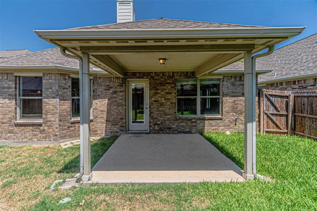 Covered patio with a concrete surface, brick exterior, and a glass-paneled door
