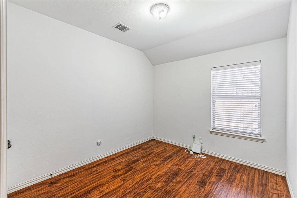 Light-filled interior featuring wood-finish flooring, white walls, and a window with blinds