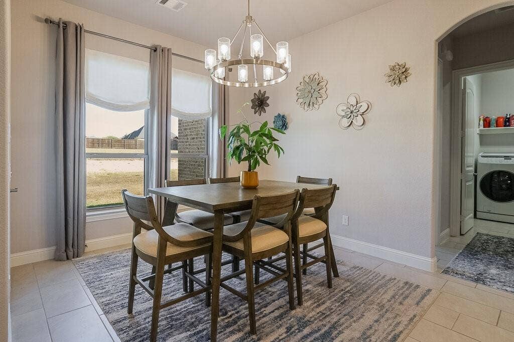 Dining area with tile flooring, a contemporary chandelier, and large windows