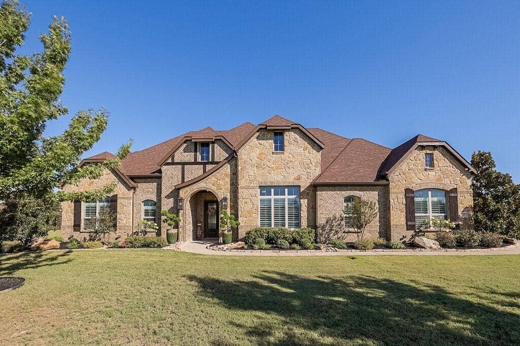 Stone and brick exterior with a brown shingle roof