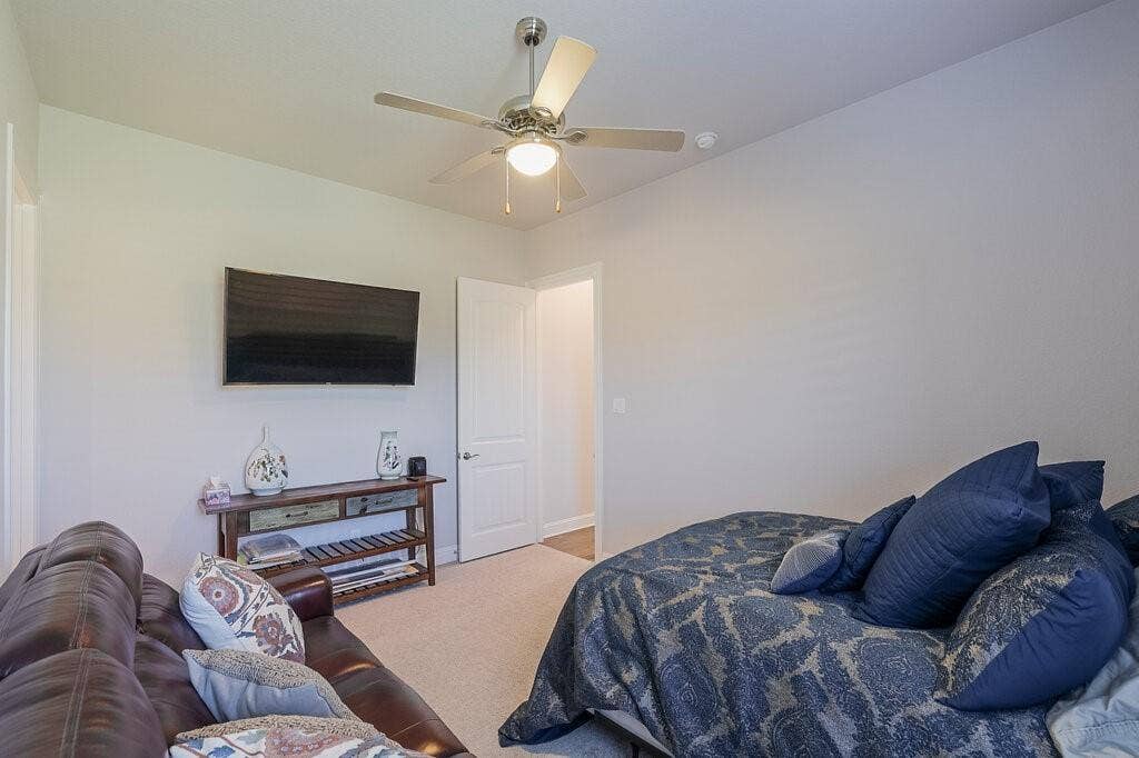 Neutral wall tones, ceiling fan with integrated lighting, and carpeted flooring