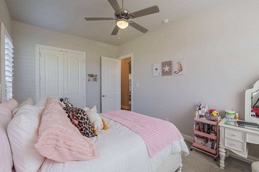 Ceiling fan with integrated lighting, window with plantation shutters, double closet doors, and a paneled interior door