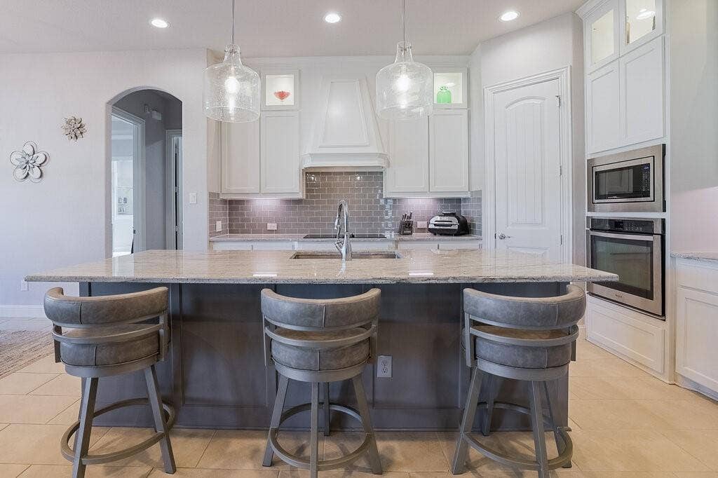 Kitchen featuring a large island, stainless steel built-in oven and microwave, recessed lighting, and tile flooring