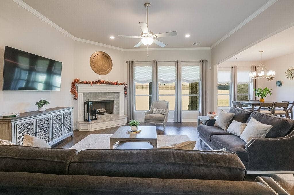 Living space featuring dark wood-finish flooring, a corner fireplace with white brick surround, recessed lighting, and a ceiling fan
