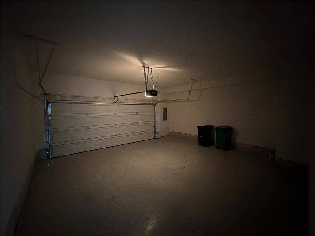 Enclosed multi-vehicle garage featuring a sectional overhead door, finished concrete flooring, and an automated garage door opener