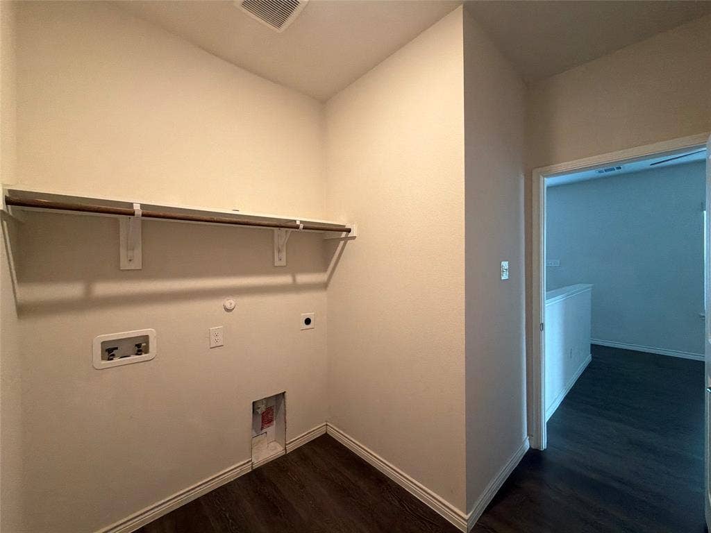 Utility area featuring wood-finish flooring, a wall-mounted shelf, and dedicated water and electrical hookups