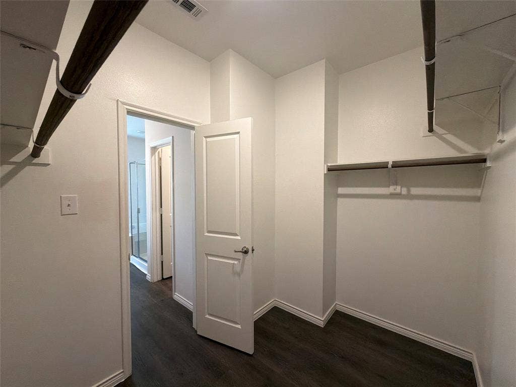 Walk-in closet featuring wood-finish flooring, built-in shelving, and dual hanging rods