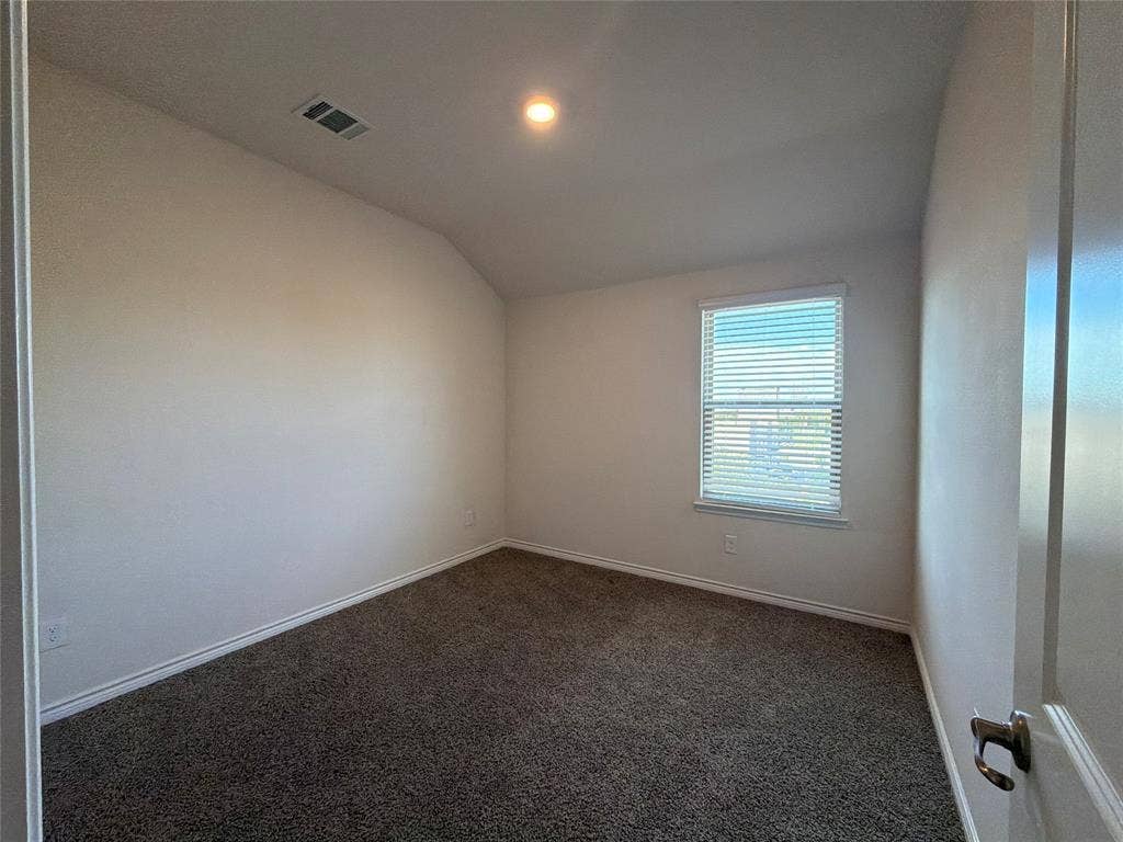 Neutral-toned interior space featuring vaulted ceilings, plush carpeting, and recessed lighting