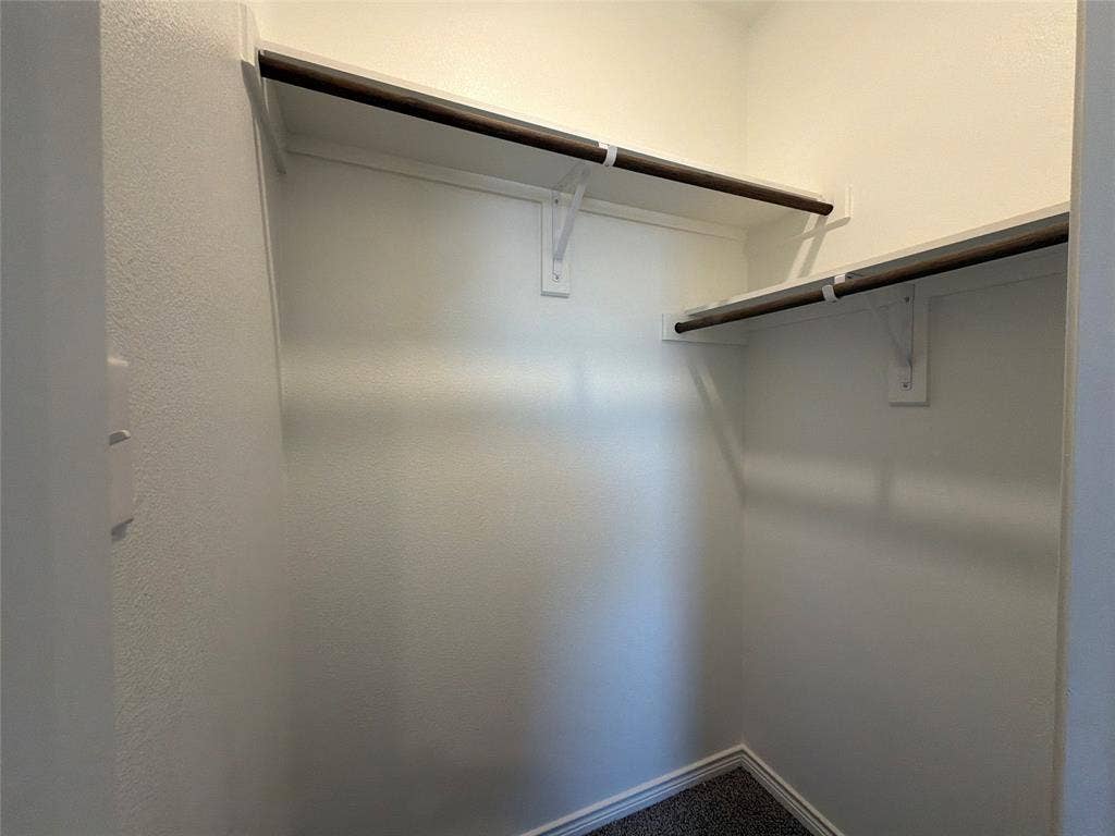 Walk-in closet featuring dual-level hanging rods and integrated upper shelving