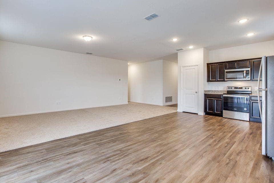 212 Briar Cove, Anna, TX 75409 Open-concept living space with wood-finish flooring, recessed lighting, and a kitchen featuring dark cabinetry, stainless steel appliances, and a light-toned countertop