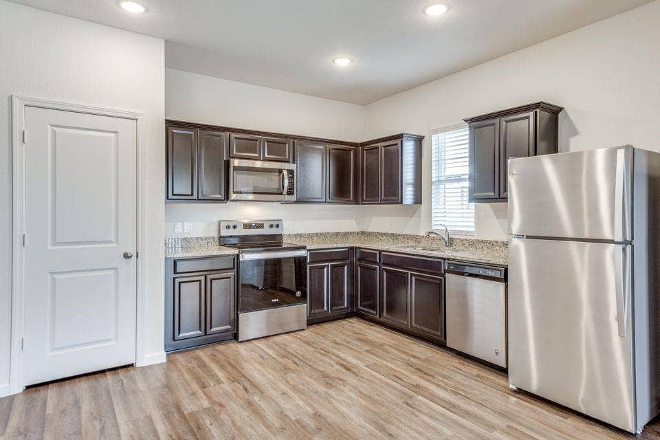 212 Briar Cove, Anna, TX 75409 Kitchen featuring dark wood cabinetry, stainless steel appliances, granite-style countertops, wood-finish flooring, and recessed lighting