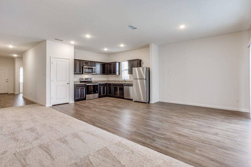 212 Briar Cove, Anna, TX 75409 Open-concept living area featuring wood-finish flooring, recessed lighting, and a kitchen with dark cabinetry and stainless steel appliances