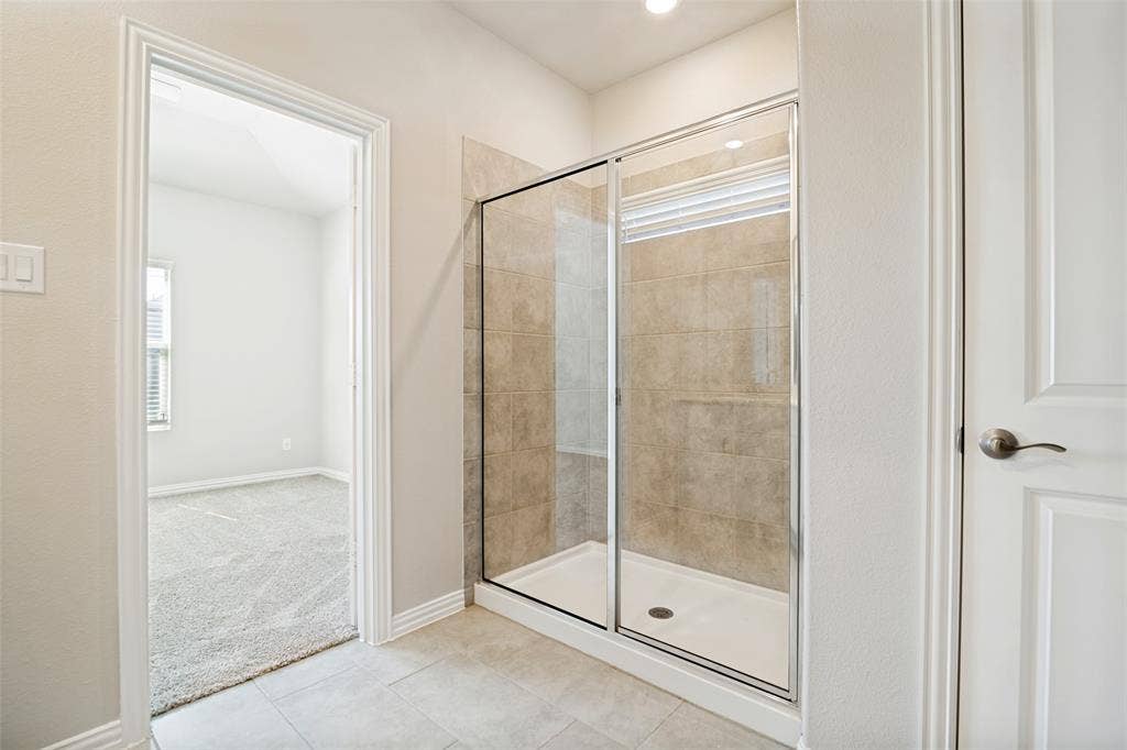 Glass-enclosed shower with tile surround, neutral wall paint, recessed lighting, and tile flooring