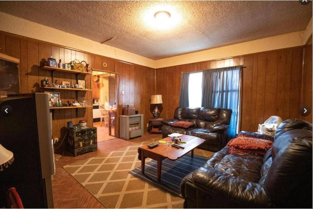 Wood paneling throughout, textured ceiling, built-in wall shelving, and wood-finish flooring