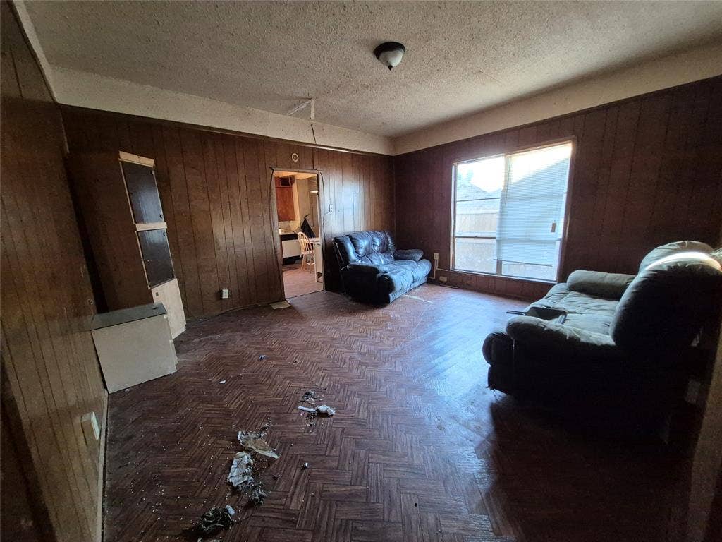 Room featuring wood paneling, parquet flooring, and a single-pane window
