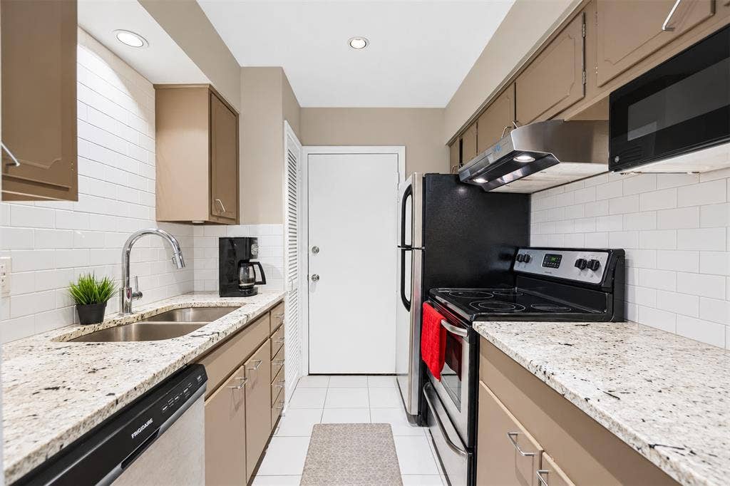 5005 Cedar Springs Road, #A, Dallas, TX 75235 Kitchen featuring granite-style countertops, subway tile backsplash, recessed lighting, and stainless-steel appliances including a built-in microwave and range hood