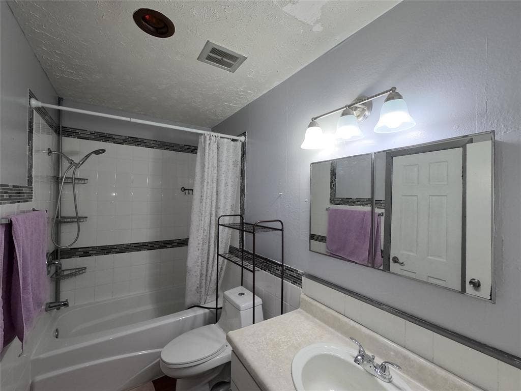 21 W Townhouse Lane, #33, Grand Prairie, TX 75052 Bathtub with white tile surround and decorative accent band, chrome shower fixture, vanity with integrated sink, chrome faucet, and mirrored medicine cabinet