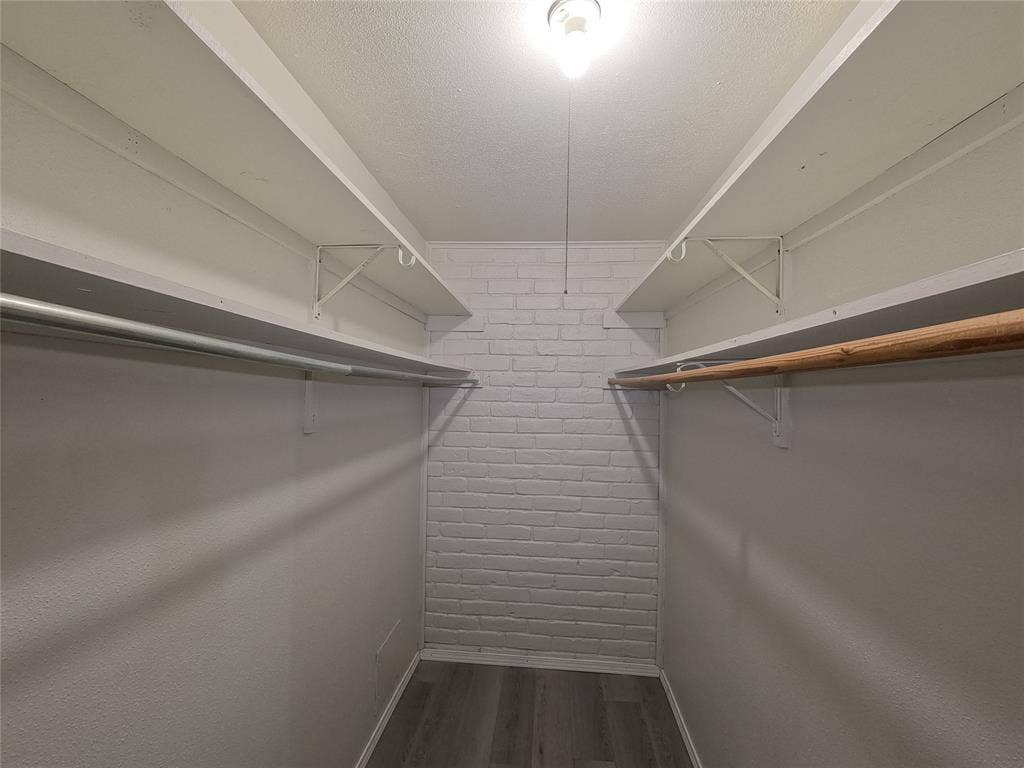 21 W Townhouse Lane, #33, Grand Prairie, TX 75052 Walk-in closet with brick accent wall, wood-finish flooring, and dual hanging rods