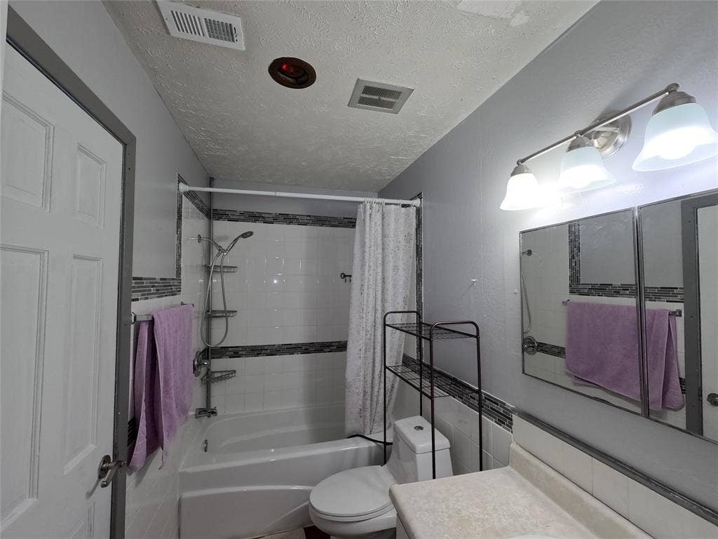 21 W Townhouse Lane, #33, Grand Prairie, TX 75052 Bathroom featuring a white bathtub, white tile surround with decorative accent band, and a vanity with a light-colored countertop