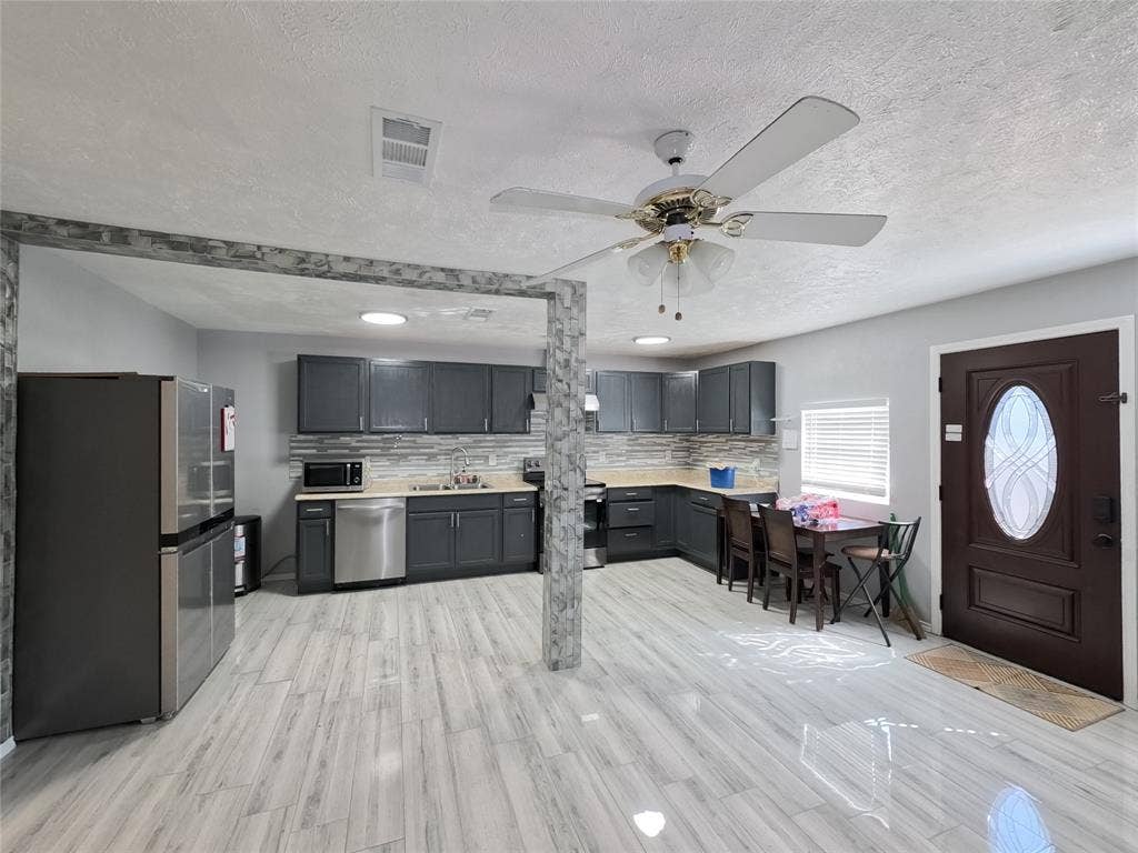 21 W Townhouse Lane, #33, Grand Prairie, TX 75052 Open-concept kitchen with dark cabinetry, light-toned countertops, and a full tile backsplash