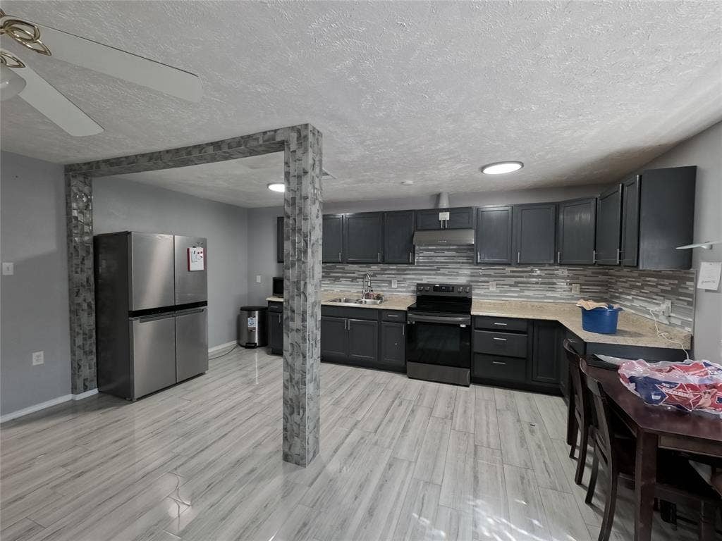 21 W Townhouse Lane, #33, Grand Prairie, TX 75052 Kitchen with wood-finish flooring, dark cabinetry, light-toned countertops, and a tiled backsplash