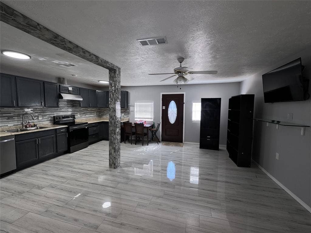 21 W Townhouse Lane, #33, Grand Prairie, TX 75052 Open-concept living space with wood-finish flooring, a contemporary kitchen featuring dark cabinetry and a tiled backsplash, and recessed lighting