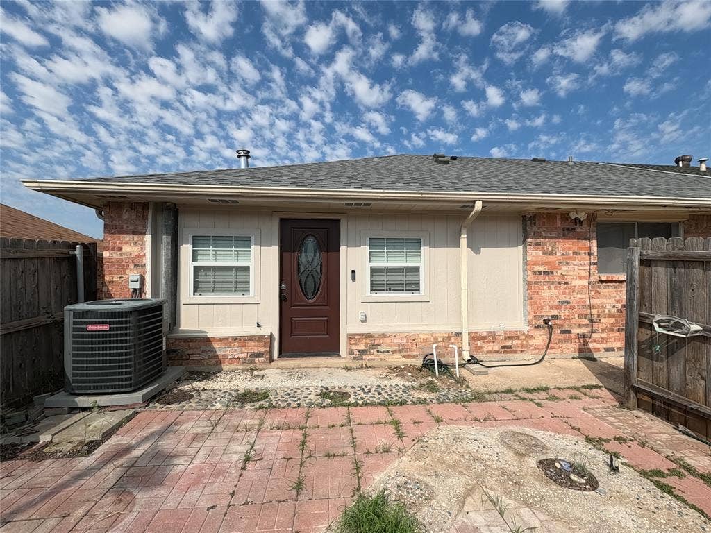 21 W Townhouse Lane, #33, Grand Prairie, TX 75052 Brick and siding exterior featuring a dark paneled entry door with an oval glass insert, two windows with blinds, and a shingle roof