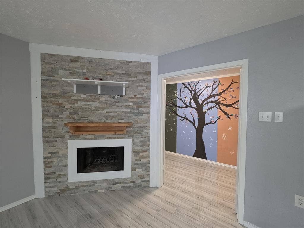 21 W Townhouse Lane, #33, Grand Prairie, TX 75052 Stacked stone accent wall with fireplace, wood-finish flooring, and a decorative wall mural