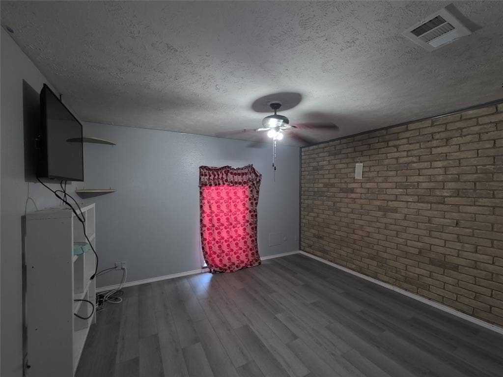 21 W Townhouse Lane, #33, Grand Prairie, TX 75052 Wood-finish flooring, accent brick wall, overhead ceiling fan with lighting, and light gray wall paint
