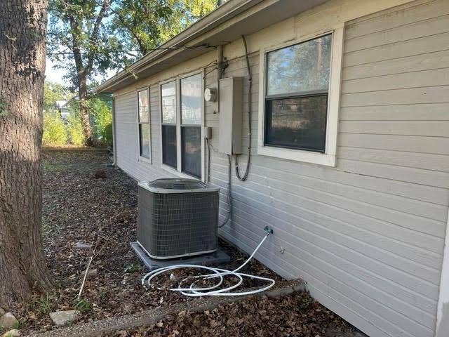 Horizontal lap siding exterior featuring multiple dual-pane windows and a central air conditioning condenser unit
