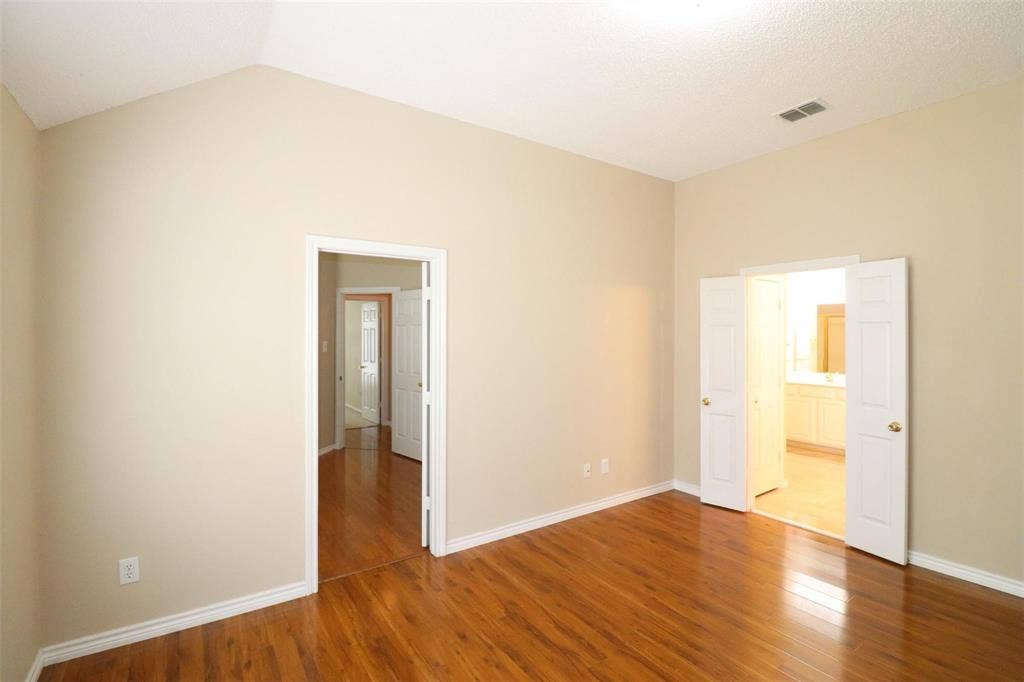 2222 Edinburgh Way, Garland, TX 75040 Vaulted ceiling, wood-finish flooring, neutral paint palette, white trim, and white paneled doors