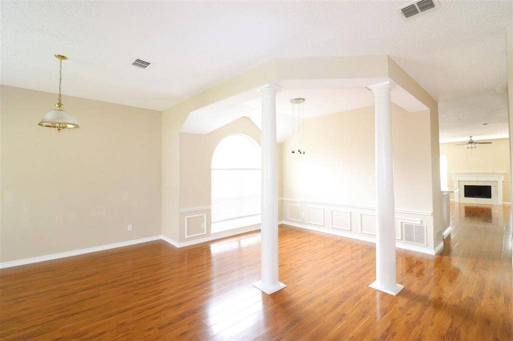 2222 Edinburgh Way, Garland, TX 75040 Wood-finish flooring, wainscoting, decorative columns, arched window, and vaulted ceiling