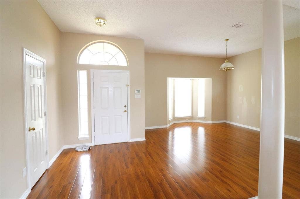 2222 Edinburgh Way, Garland, TX 75040 Entryway featuring a white paneled door with sidelights, a transom window, and wood-finish flooring