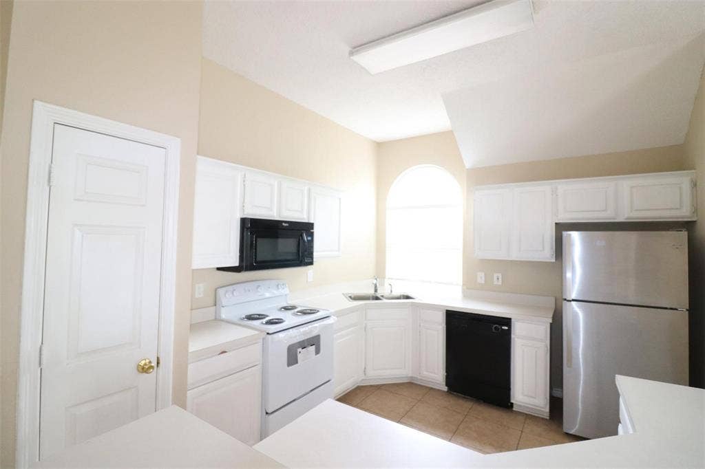 2222 Edinburgh Way, Garland, TX 75040 Kitchen featuring white cabinetry, white countertops, built-in microwave, stainless steel refrigerator, and an arched window
