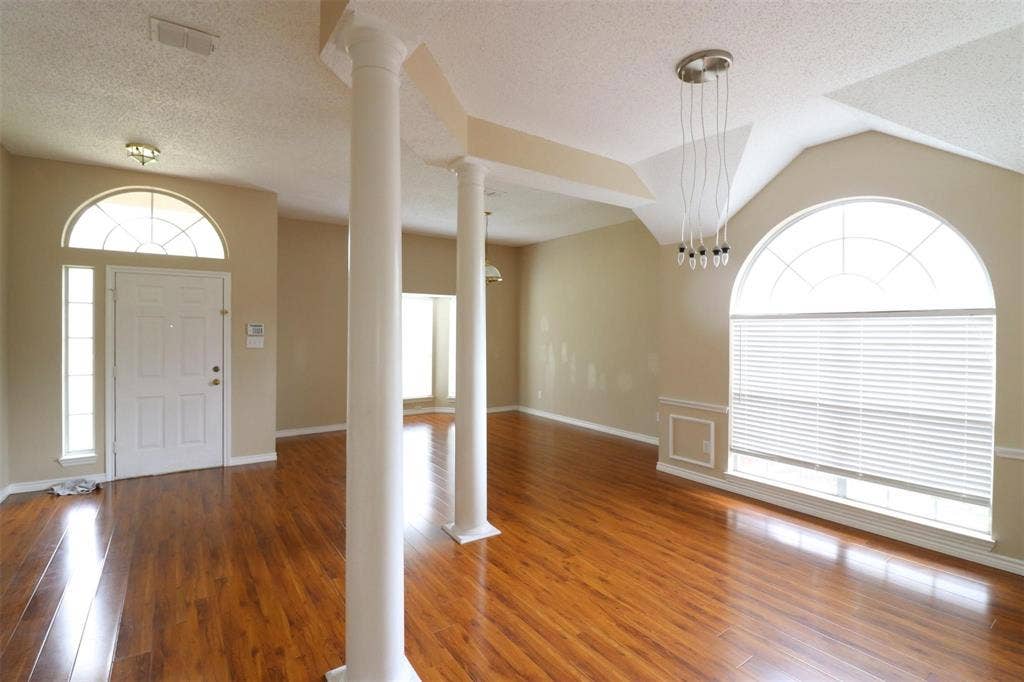 2222 Edinburgh Way, Garland, TX 75040 Wood-finish flooring throughout, featuring decorative columns, and a front entry with sidelights and an arched transom window