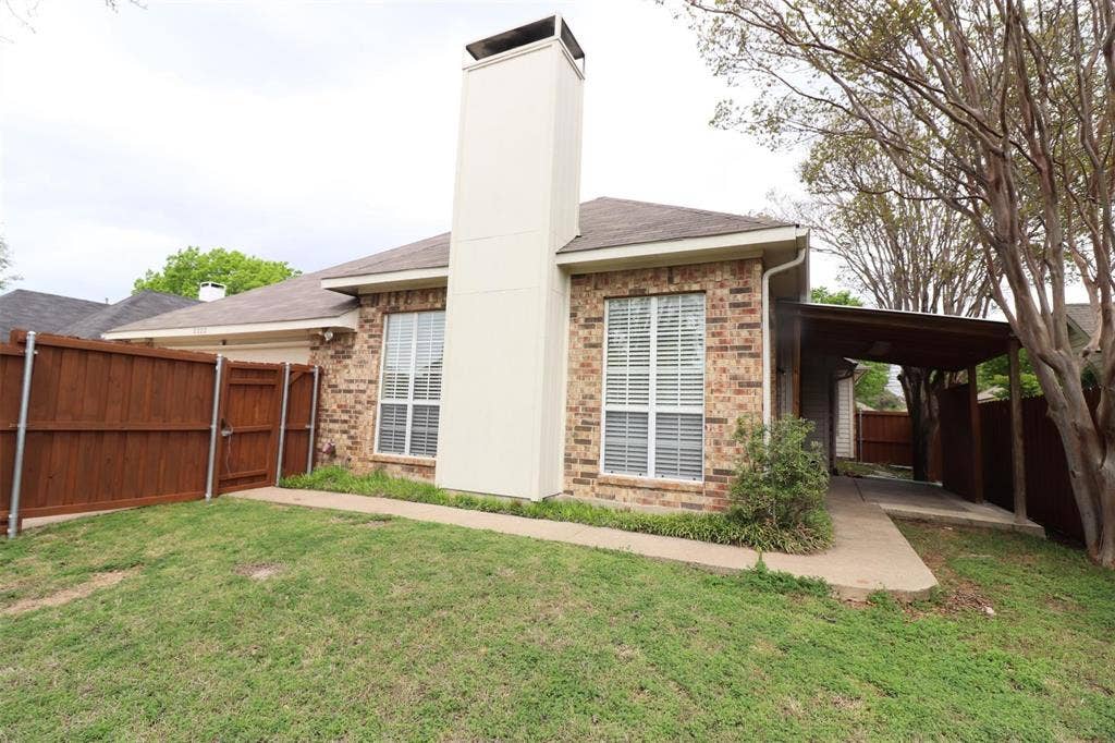 2222 Edinburgh Way, Garland, TX 75040 Brick exterior with an integrated carport, a prominent chimney structure, and a perimeter wood fence
