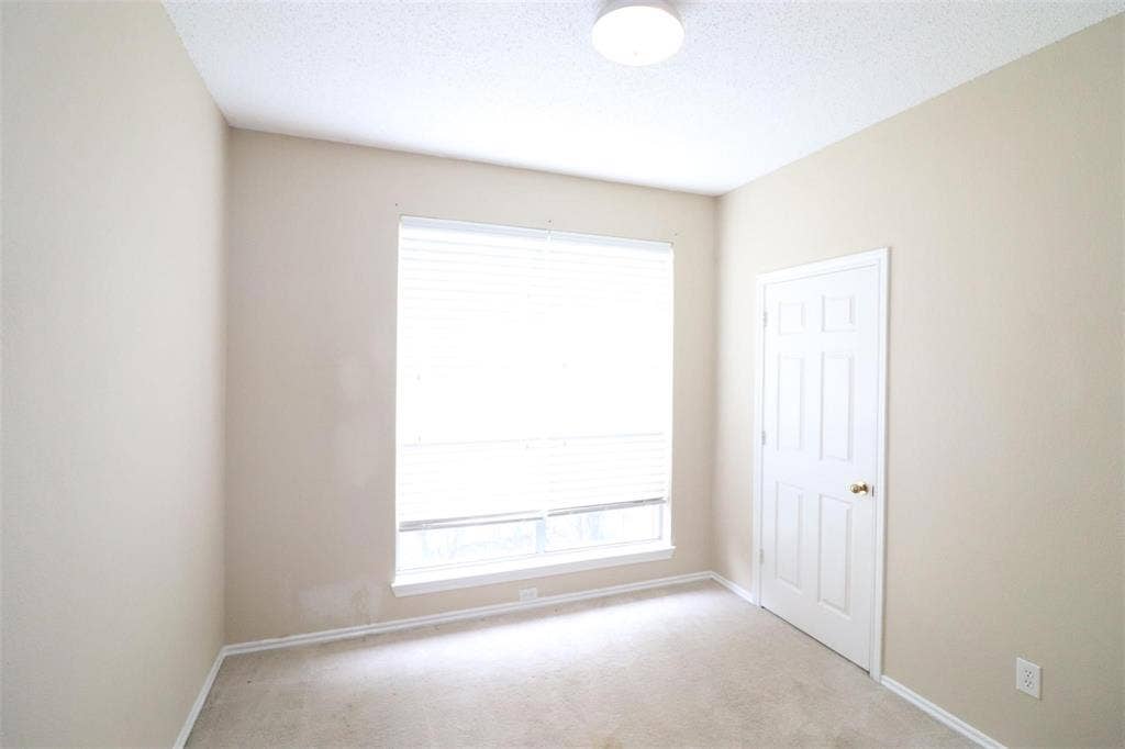 2222 Edinburgh Way, Garland, TX 75040 Neutral wall paint, textured ceiling, flush mount ceiling light, six-panel interior door with brass hardware, and a window with blinds