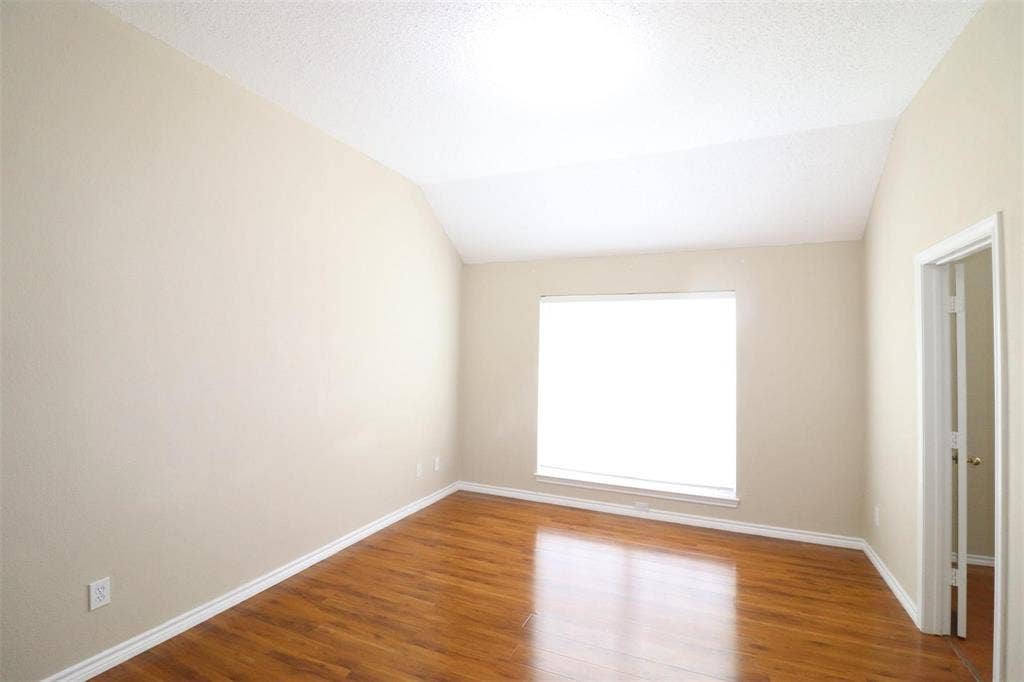2222 Edinburgh Way, Garland, TX 75040 Vaulted ceiling, wood-finish flooring, neutral paint, single window with blinds, and white trim throughout