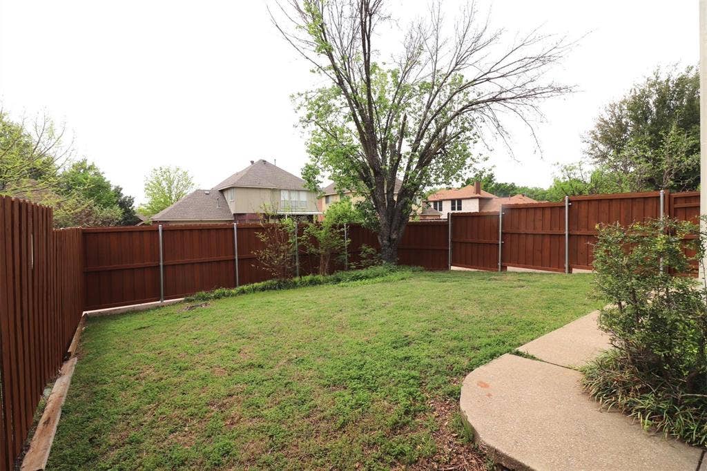 2222 Edinburgh Way, Garland, TX 75040 Expansive backyard featuring a natural grass lawn, wood plank fencing, and mature trees