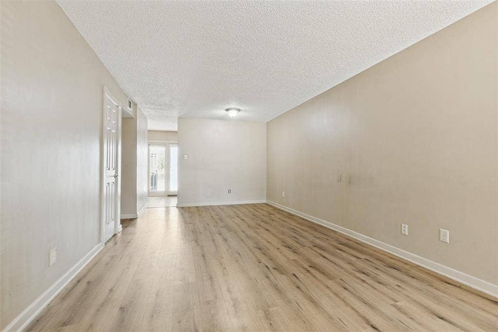2111 E Belt Line Road, #158B, Richardson, TX 75081 Spacious room with wood-finish flooring, light-colored walls, white trim, and a ceiling-mounted light fixture