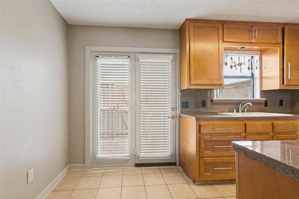 2111 E Belt Line Road, #158B, Richardson, TX 75081 Warm wood cabinetry with brushed nickel hardware, granite-look countertops, and a stainless steel sink with a gooseneck faucet
