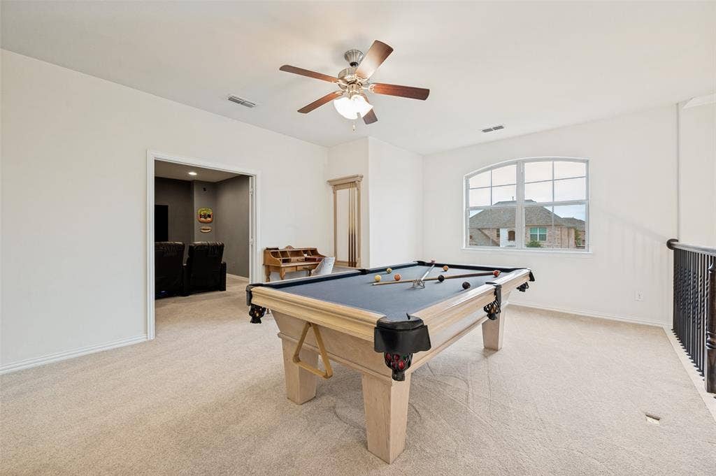 131 Darian Drive, Prosper, TX 75078 Carpeted room featuring a ceiling fan with light, an arched window, and a wrought iron railing