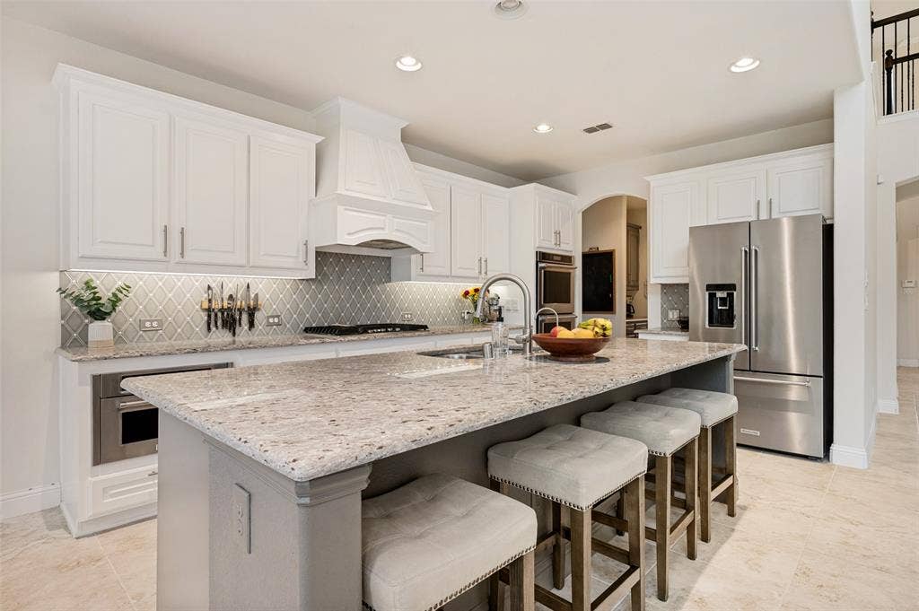 131 Darian Drive, Prosper, TX 75078 White cabinetry, stainless steel appliances, large kitchen island with light-toned countertop, recessed lighting, and tile flooring