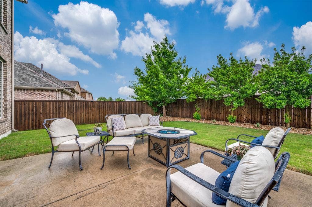 131 Darian Drive, Prosper, TX 75078 Private backyard featuring a concrete patio, wood privacy fence, and manicured lawn with mature trees